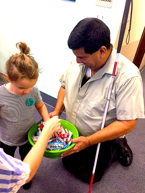 Pete is handing out halloween candy to a lot of children.